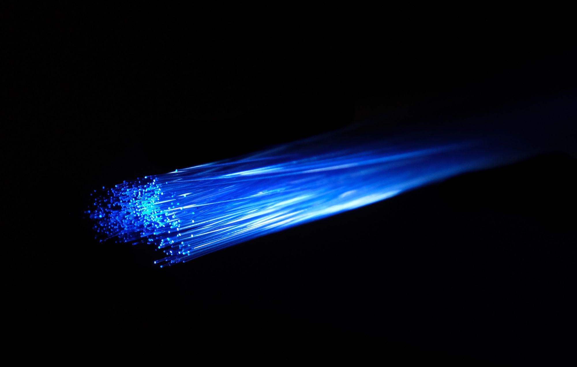 Stock image of a blue light passing over fibre optic cable. 